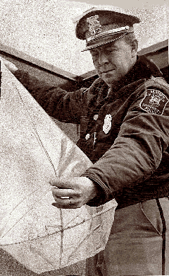 John E. Hayes, chef de la police de l'Université du Michigan de l'Est, examine un faux ovni de      Yipsilanti composé d'un sac en plastique, d'une croix en plastique et de quelques chandelles
